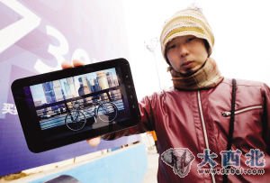 昨天，在楚河汉街，河源启一郎将他的自行车图片展示给路人看。记者陈亮 摄  
