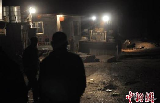 22日晚11时，有大型铲车正在清理运石车上翻落的石块。　吕子豪　摄